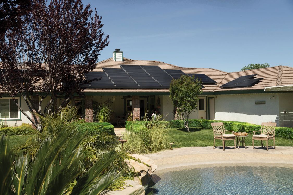 Paneles solares térmicos en el techo de una casa moderna con cielo azul